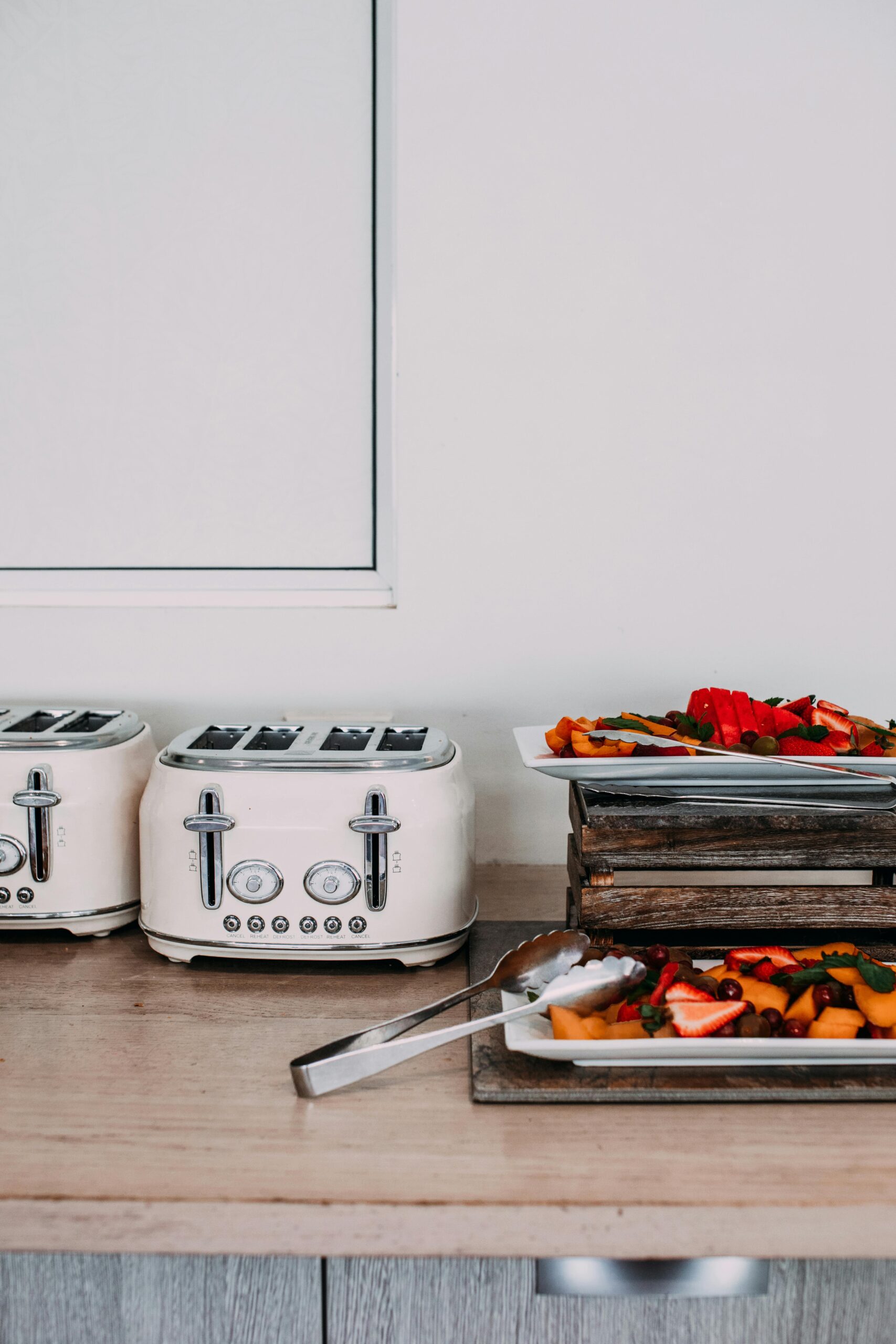 Modern kitchen scene with toasters and assorted fruit trays on a countertop.